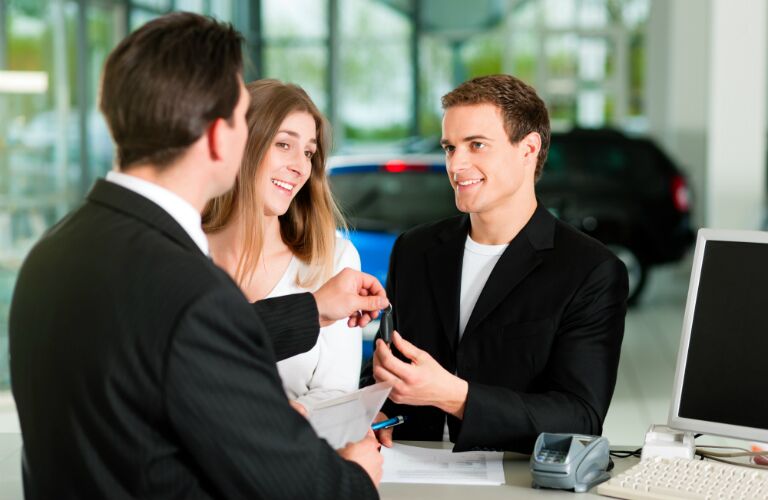 Young couple getting keys to a new car