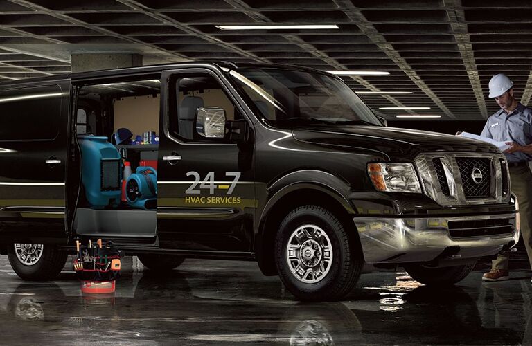 man in hard hat next to black 2018 nissan nv cargo van with doors open and supplies inside