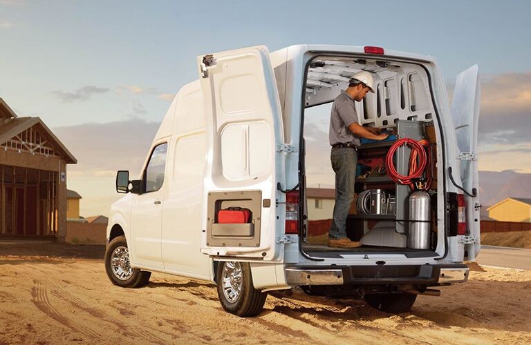 man in hard hat in rear of white 2018 nissan nv cargo van at construction site