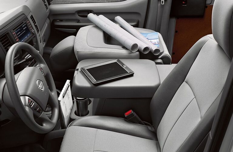 front interior of 2018 nissan nv cargo van with passenger seat folded down and electronics and papers on it