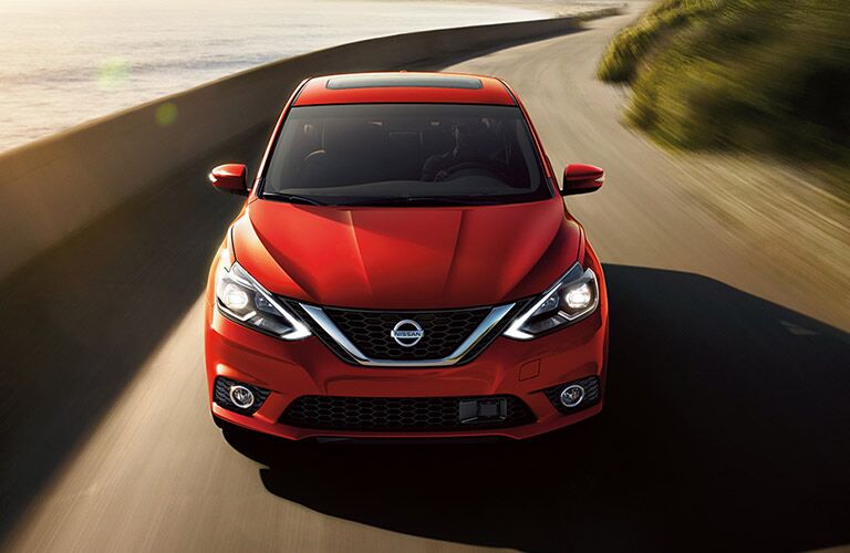 red 2018 nissan sentra driving on ocean road