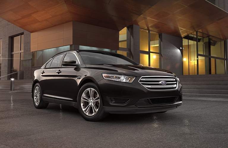 Wider shot of 2018 Ford Taurus parked in front of modern-styled building