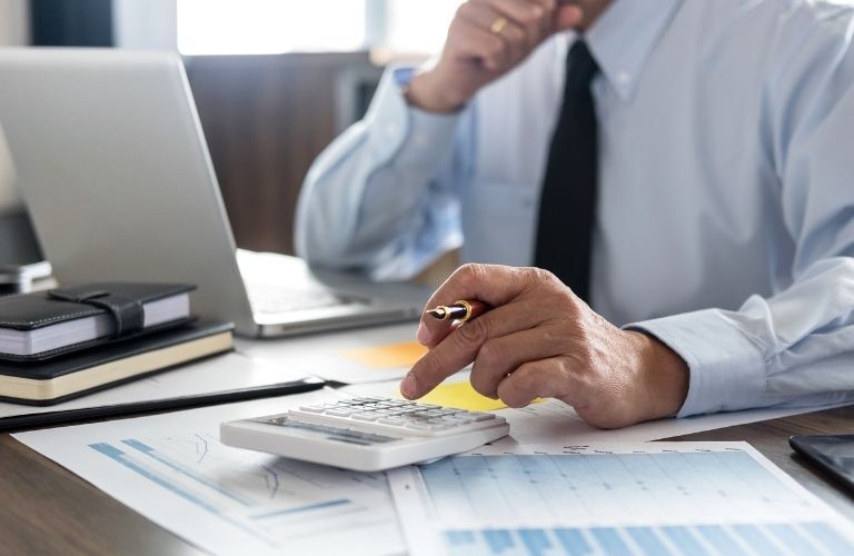 A man working on a calculator and a laptop