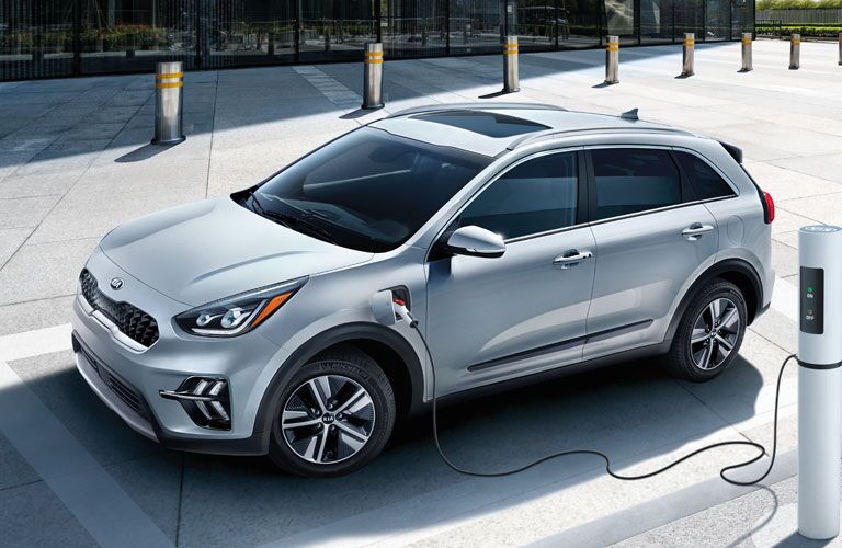 A used Kia Niro being charged in a parking lot.