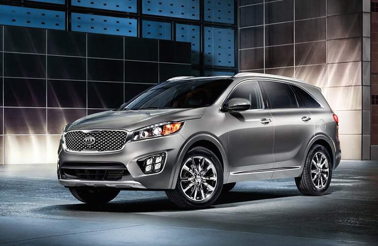 A front left quarter image of a gray Kia Sorento in front of a building