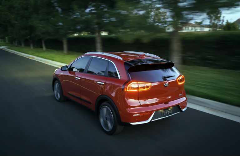 A rear left quarter photo of the 2018 Kia Niro driving on the road at night.