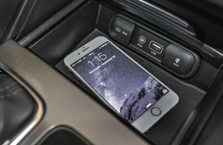 A close up photo of a smartphone sitting in a tray inside of the 2018 Optima.