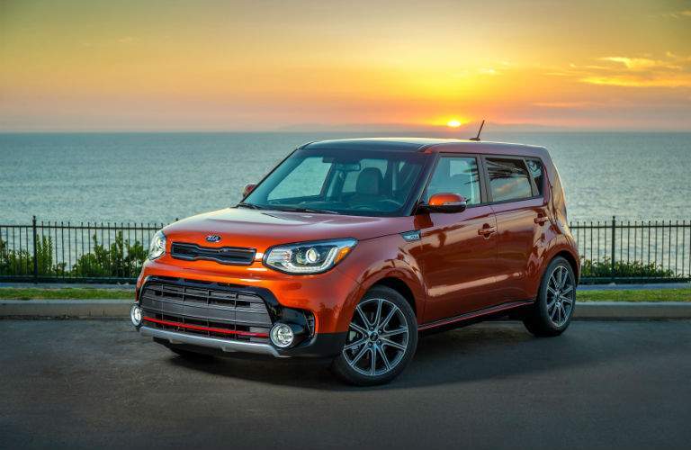A left front quarter view of an orange 2018 Kia Soul parked in front of the ocean