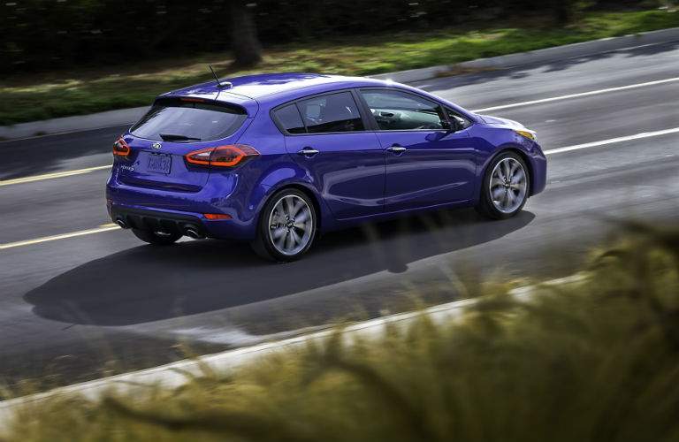 A right profile view of a blue 2018 Kia Forte hatchback model on the road