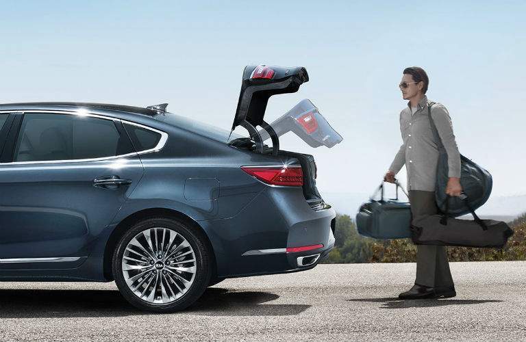 man loading luggage into trunk of blue 2018 kia cadenza with motion activated lift gate