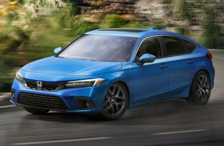 Front view of a blue 2022 Honda Civic Hatchback cornering a road
