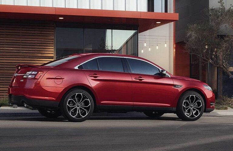 rear and side view of red 2019 ford taurus in front of modern home