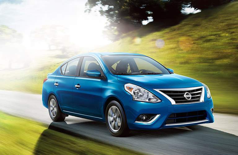 blue nissan versa driving, sunny skies