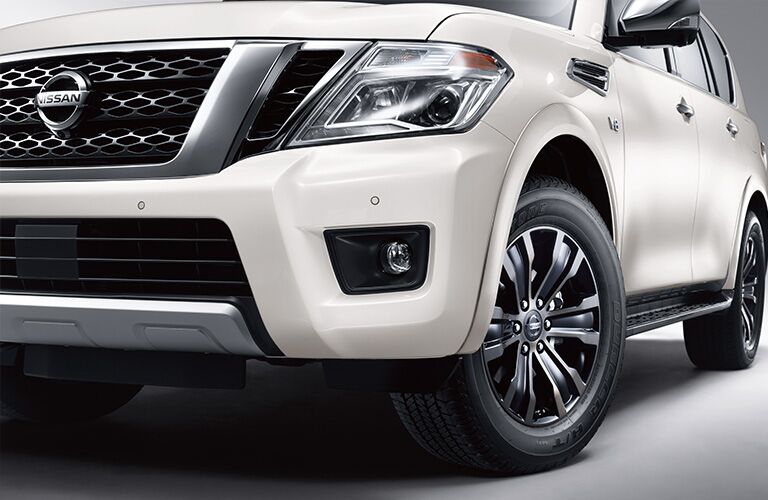 Exterior view of the front headlight, grille, and tire on a white 2019 Nissan Armada