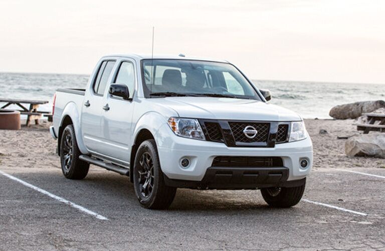 Exterior view of a white 2019 Nissan Frontier parked in a parking lot at the beach
