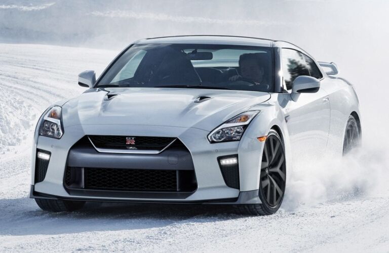 Exterior view of the front of a white 2019 Nissan GT-R driving in the snow