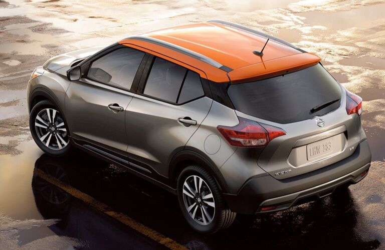 Exterior view of a gray and orange 2019 Nissan Kicks parked in a wet parking lot