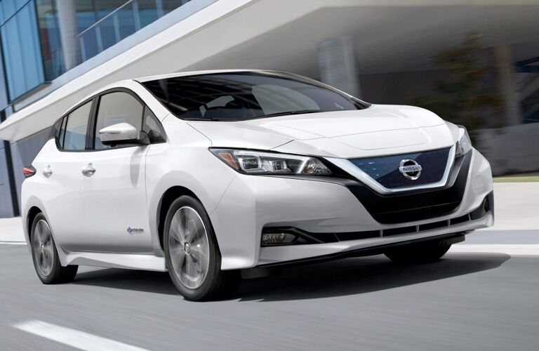 Exterior view of a white 2019 Nissan Leaf driving down a city street