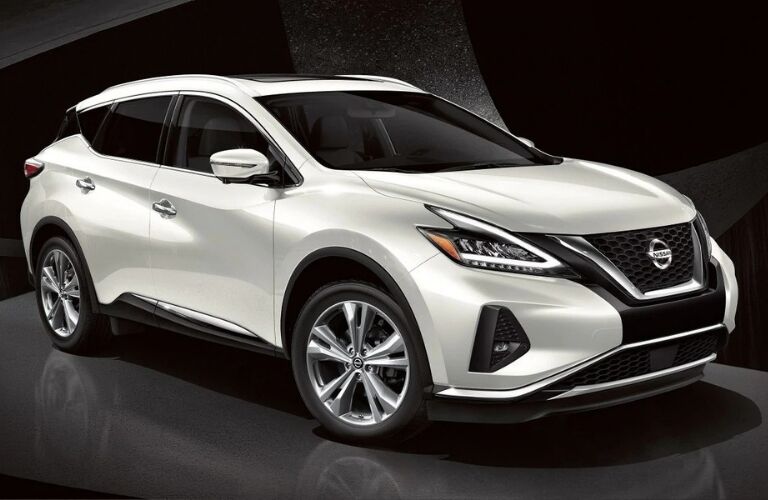 Exterior view of white 2019 Nissan Murano parked in a black showroom