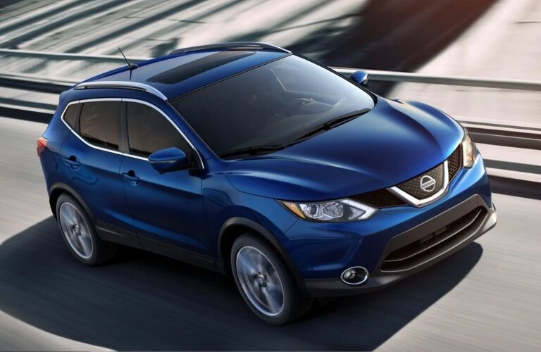 Exterior view of the front of a blue 2019 Nissan Rogue Sport driving down the highway