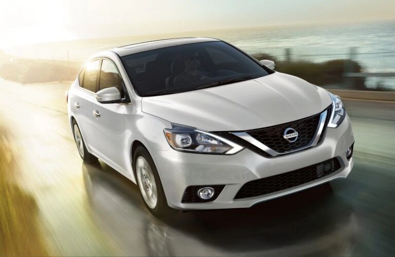 Exterior view of a white 2019 Nissan Sentra driving down a coastal highway