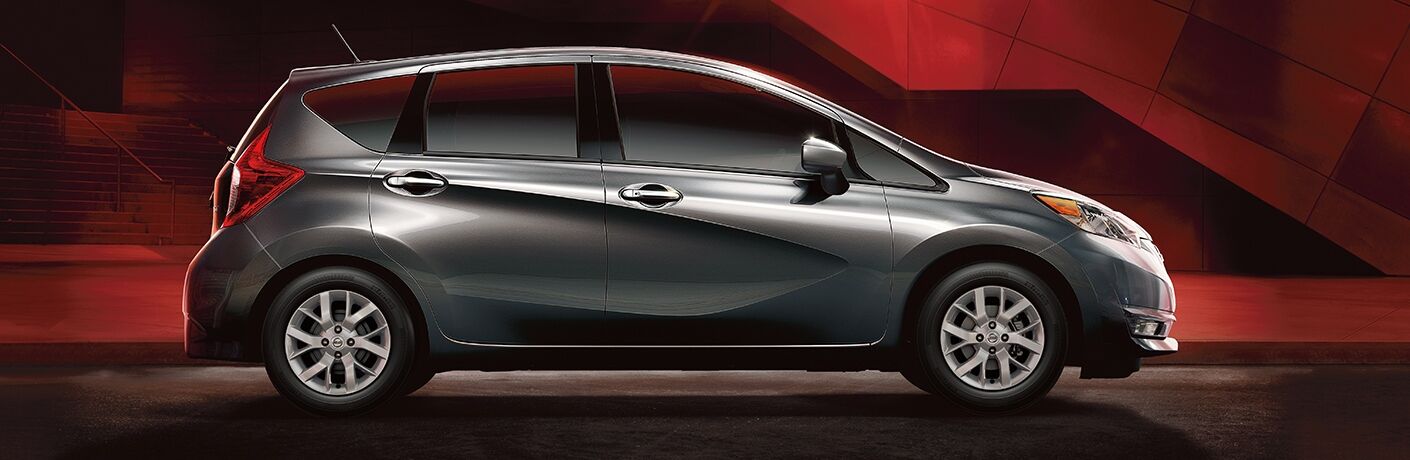 Exterior view of a grey 2019 Nissan Versa Note parked in a black and red showroom