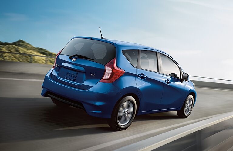 Exterior view of the rear of a blue 2019 Nissan Versa Note driving down the highway