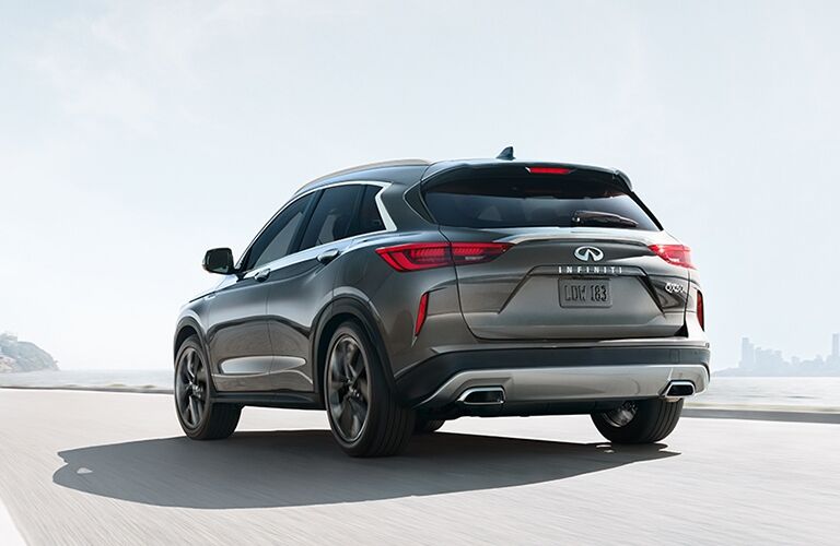 Exterior view of the rear of a grey 2019 INFINITI QX50 driving down the highway