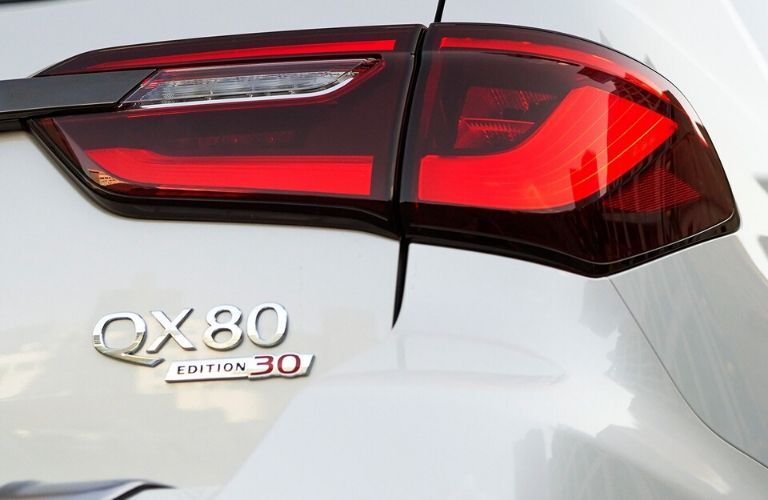 Closeup exterior view of the rear and "QX80" badge on a white 2020 INFINITI QX80