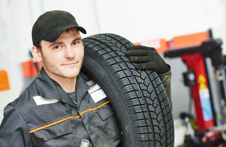 Mechanic with a tire over his shoulder