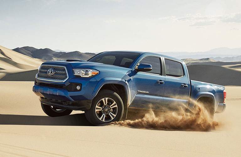 Blue Toyota Tacoma playing in the sand