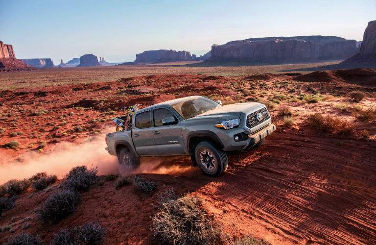 A photo of a 2018 Toyota Tacoma going over a hill on a desert trail