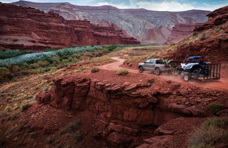 A photo of a 2018 Toyota Tacoma pulling an off-road vehicle over a trail