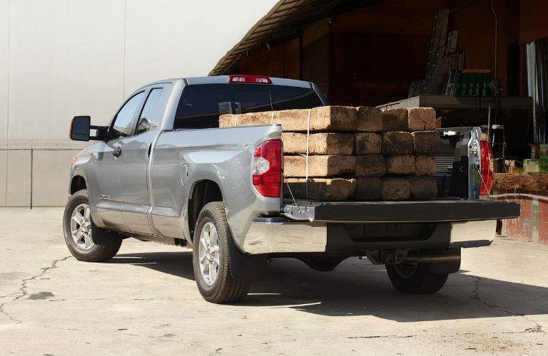 A gray 2018 Toyota Tundra with a heavy load of lumber in the cargo bed, demonstrating its engine power