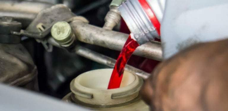 A photo of transmission fluid being poured into a vehicle as a part of an oil change.