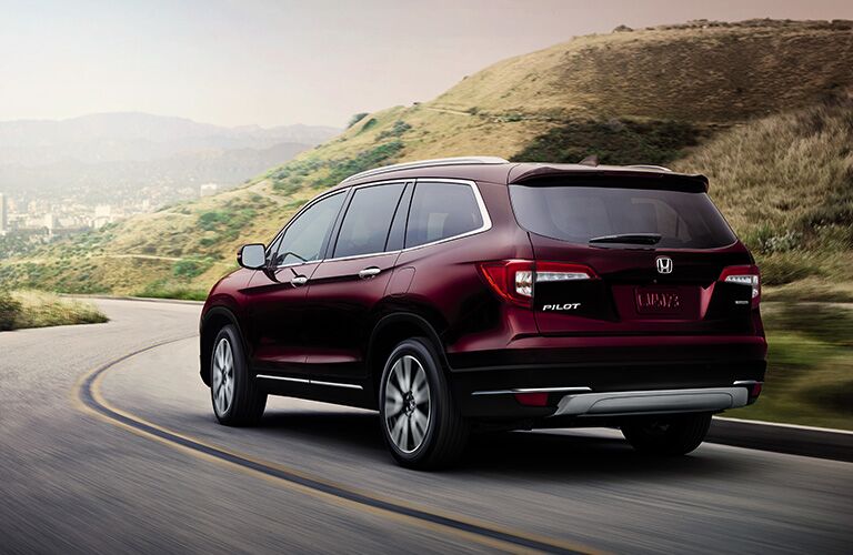 A rear left quarter photo of the 2019 Pilot in motion on the road.