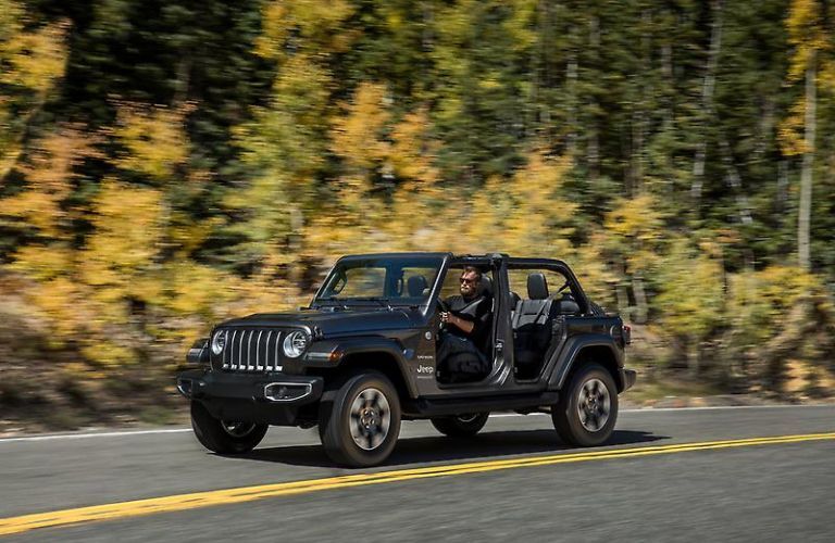 A man driving the 2023 Jeep Wrangler Sahara on road