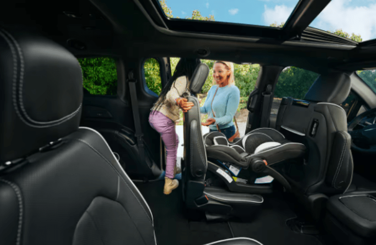 A kid sliding the seat to come out of the 2024 Chrysler Pacifica