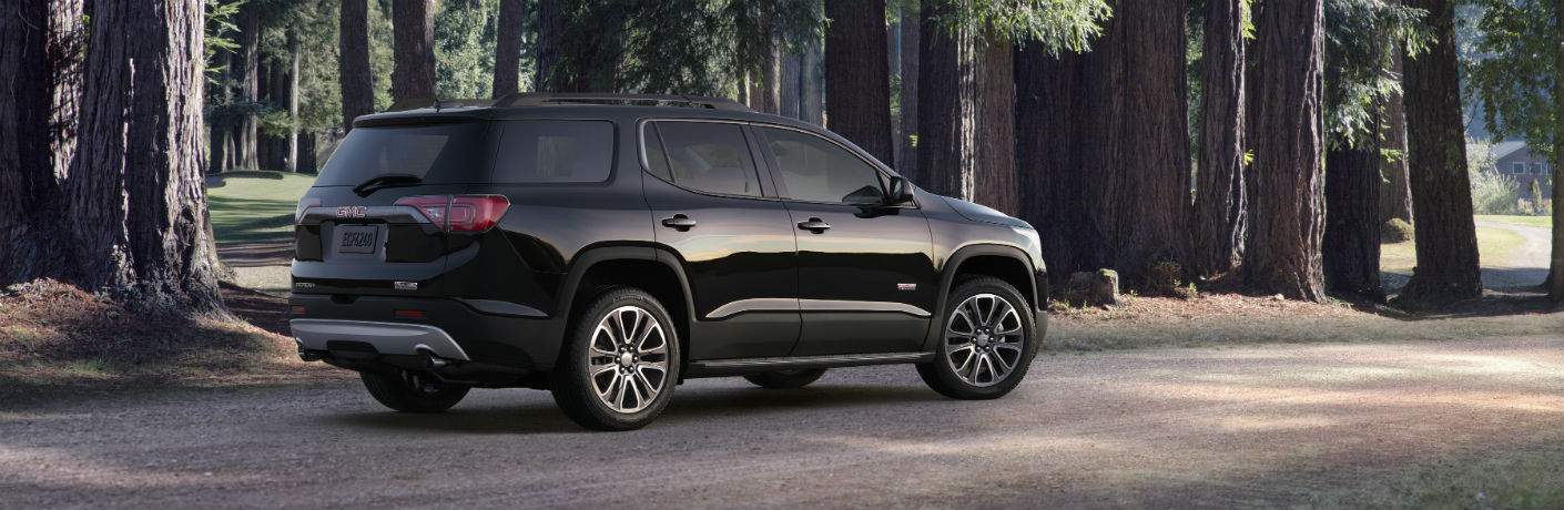 A right profile view of a black 2018 GMC Acadia in the forrest