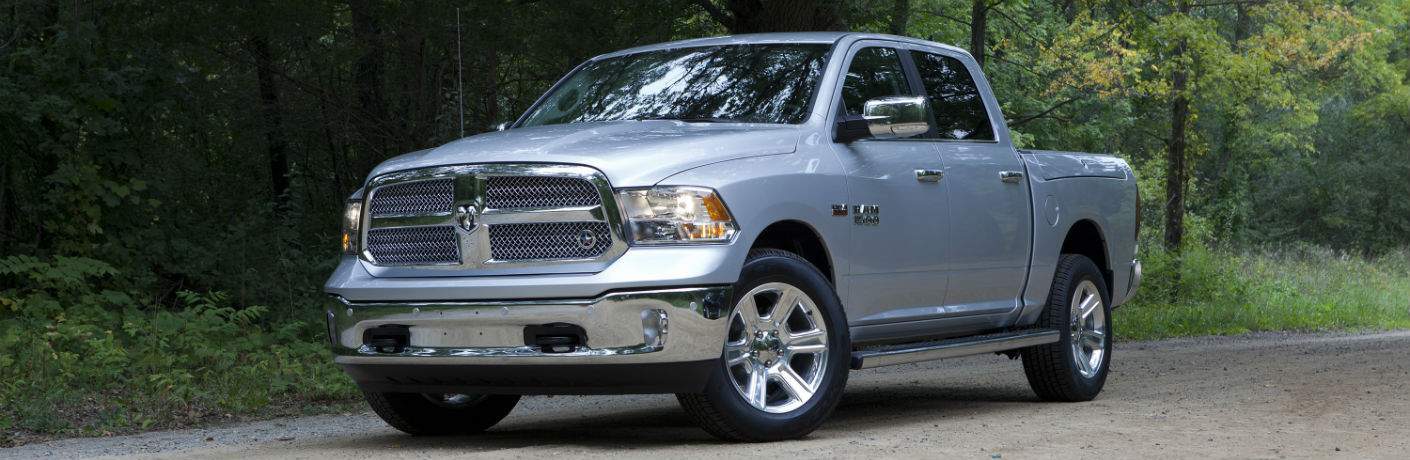 A left front quarter view of a silver 2018 Ram 1500 pickup truck in the woods
