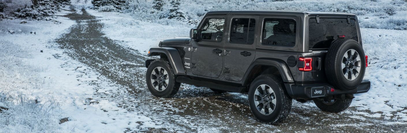 A left profile photo of a four-door version of the 2019 Jeep Wrangler on an off-road trail.