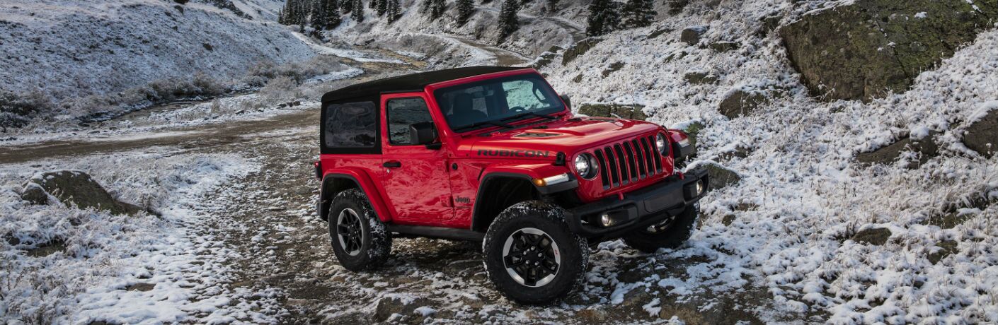 A front right quarter photo of the 2019 Jeep Wrangler climbing a snow-covered hill.
