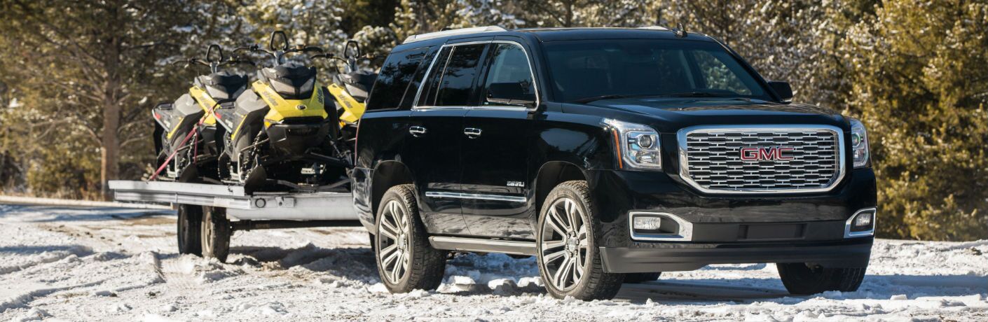 A front-right quarter photo of the 2019 GMC Yukon Denali pulling a trailer.