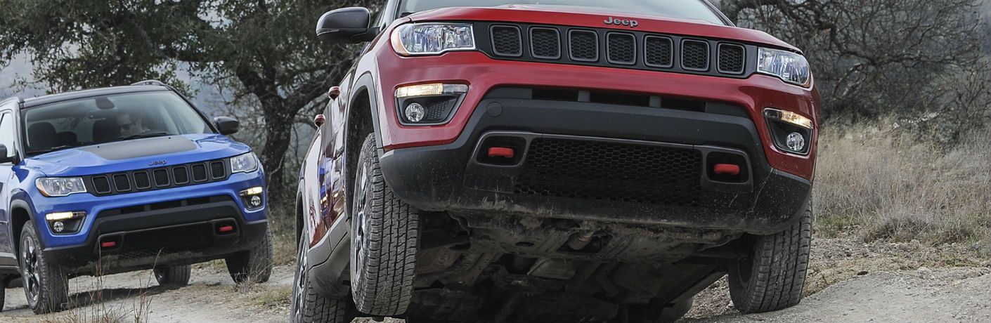 A photo of two 2019 Jeep Compass models crossing rough terrain with ease.