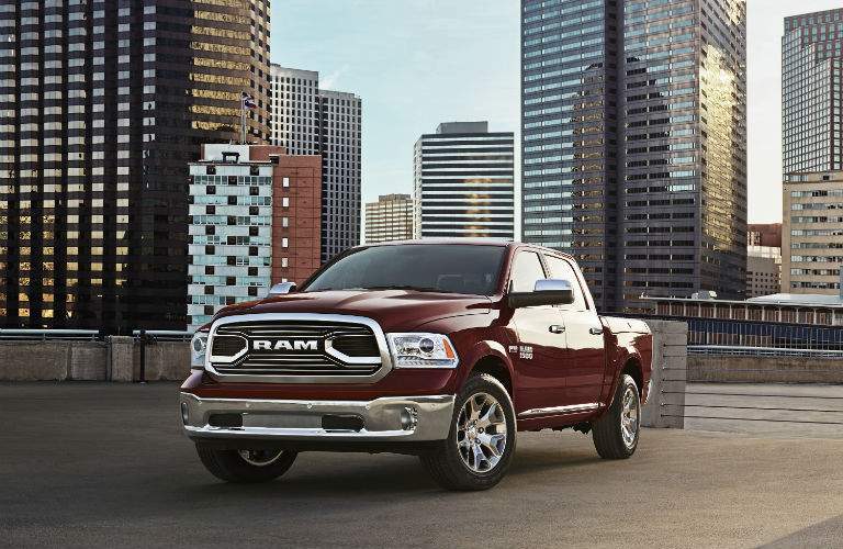 A front left view of a dark red 2018 Ram 1500 in front of a city skyline.
