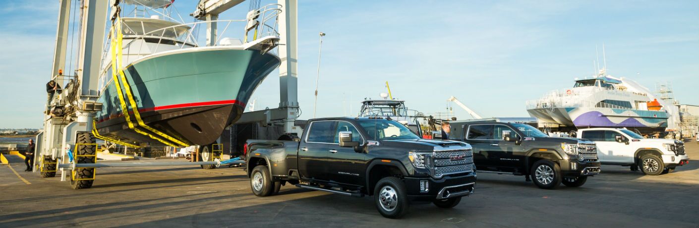 A photo of three versions of the 2020 GMC Sierra 2500HD lined up at a ship yard.