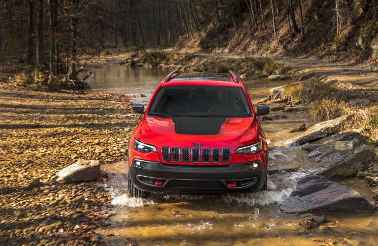 A photo of a 2019 Jeep Cherokee going through a mud hole.