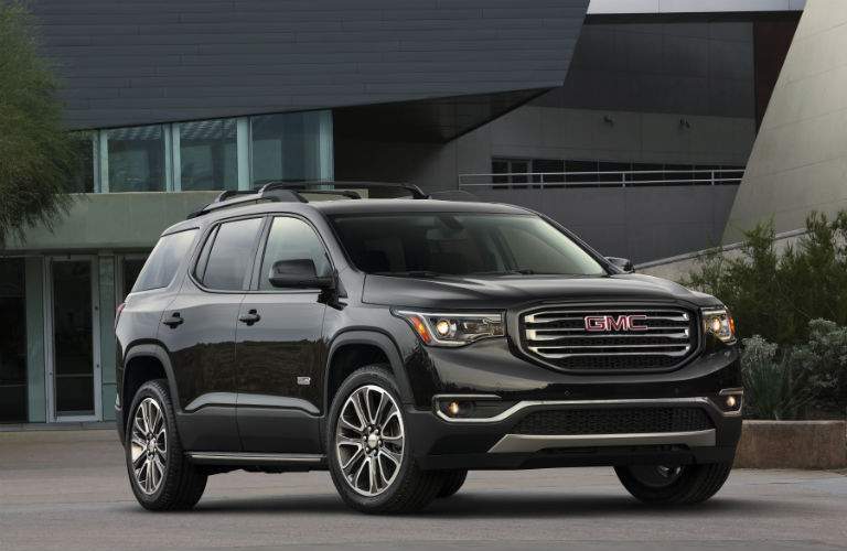 A photo of the 2018 GMC Acadia in front of a performing arts center showing one of several unique grille designs