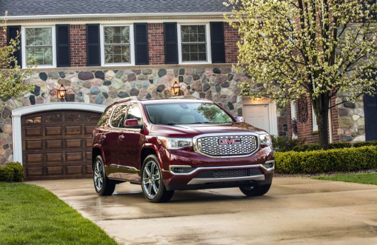 A front right profile photo of the 2018 GMC Acadia parked in front of a home.