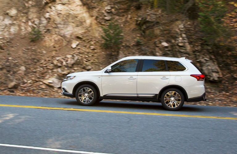 2018 Mitsubishi Outlander driving along a wooded, dirt cliff